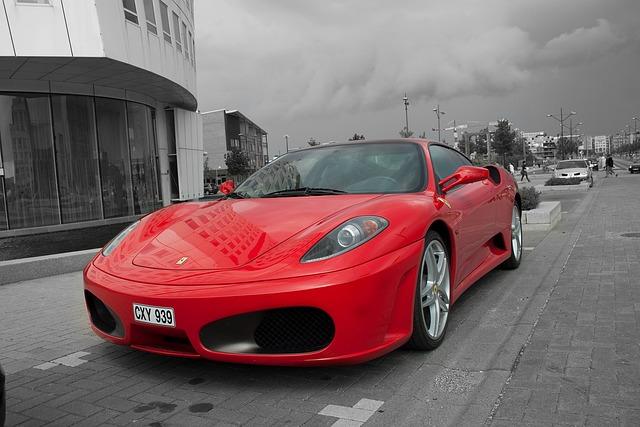 A red ferrari F430 parked out front of a car dealership.