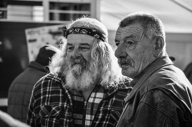 Two grizzled old men, one wearing a bandana, with long hair and a long beard.