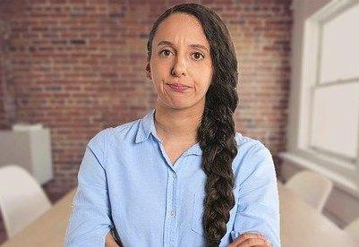 Young woman looking directly at us with an annoyed expression and crossed arms.