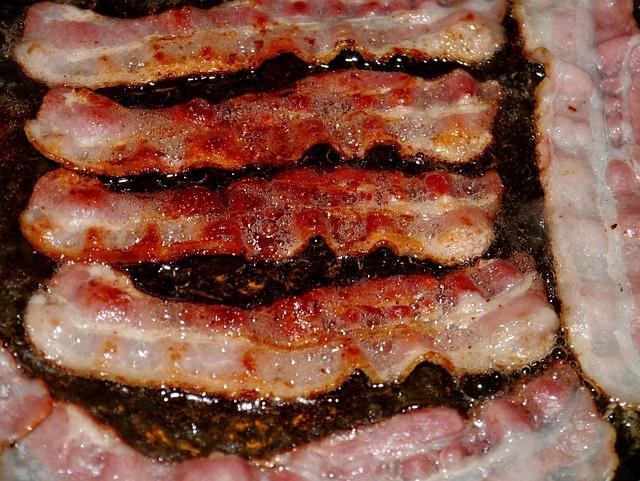 A close-up of bacon cooking in a frying pan.