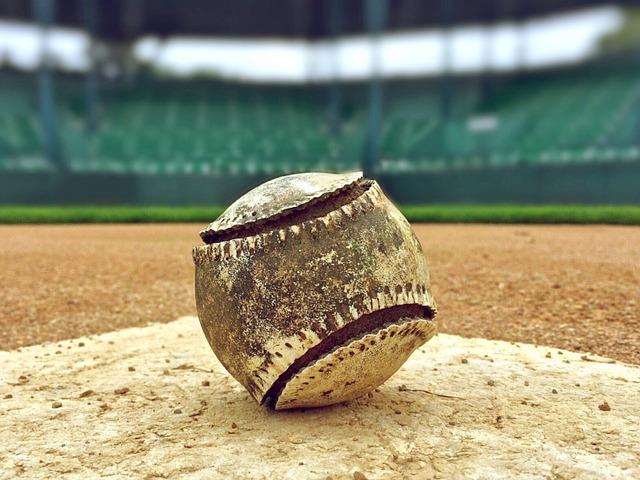 A well-used dirty baseball atop the pitcher's mound, blurry stands for the backdrop.