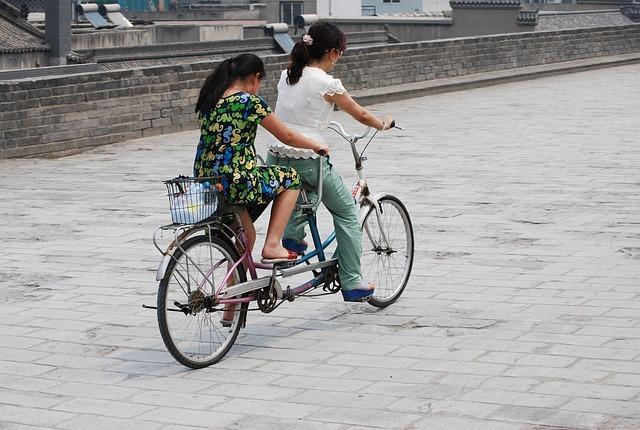 A bicycle built for two, being ridden by two young women.