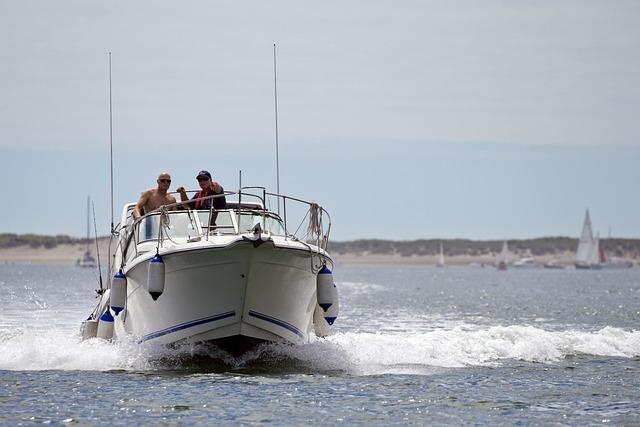 A powerboat driving directly toward us with bumpers out and wake visible.