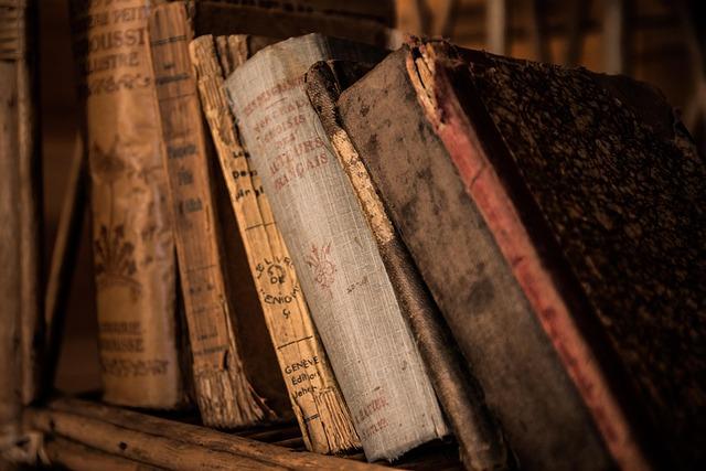 Old books leaning over on an old bookcase.