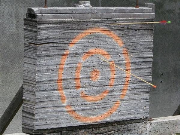 A bullseye drawn on a board with 2 arrows randomly stuck in it.