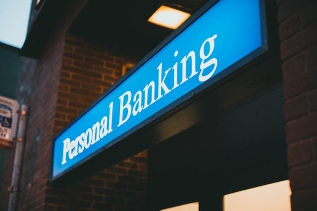 A blue sign at the front of a brick building that reads "Personal Banking" in white letters.