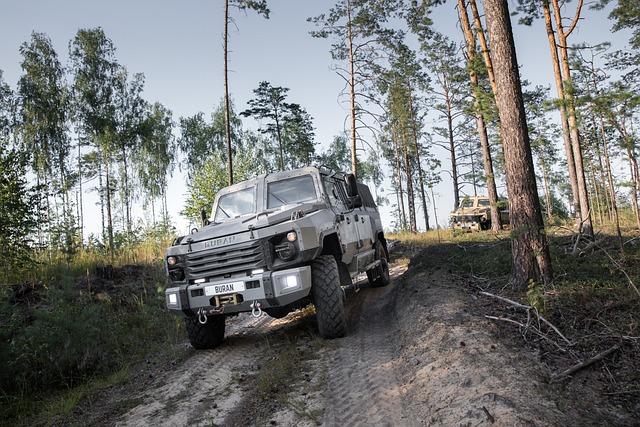 An SUV off-roading on a dirt road in a sparse forest.