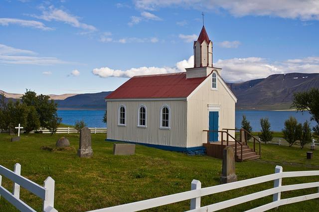 Small white country church with a cemetery and white fence.