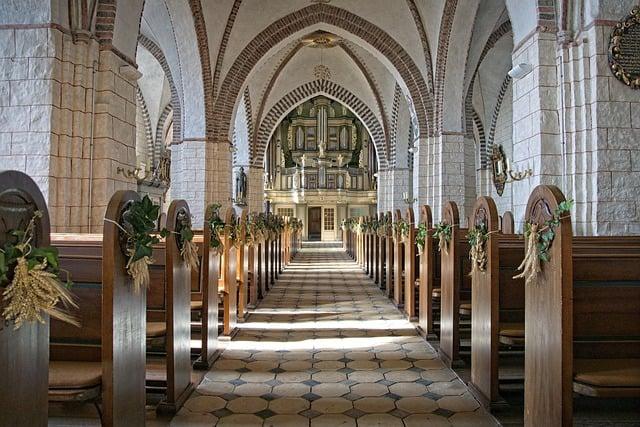 Inside of a catholic church, looking along the empty center aisle.