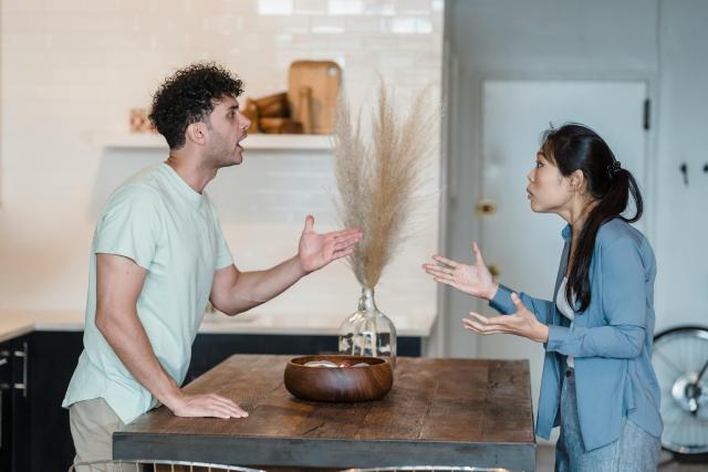 A couple mid-argument with a kitchen island between them.