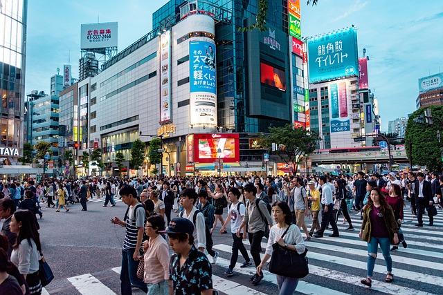 hundreds of people crossing a busy intersection in Japan