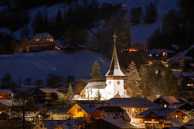 A winter village at night with a church visible in white light.