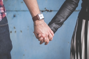 A close-up of the hands of a couple holding hands.