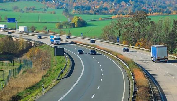 A 4-lane highway traveling through green pasture land in early autumn.