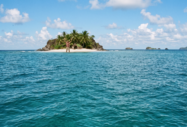 A man waving from the shore of a small deserted island.