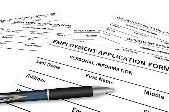 Blank job application papers on a desk with a pen sitting on top.