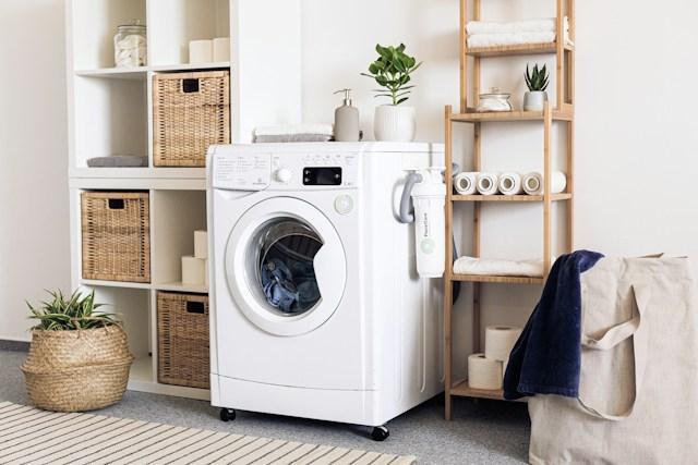 A tidy laundry room with a white washing machine and 2 tidy shelving units on either side of it.