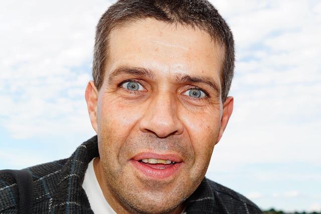 A close up of a middle-aged white man with big eyes and a confused expression.