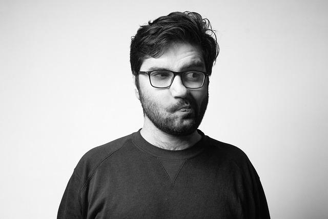 A black and white photo of a middle-aged man with a short beard, looking off to the side thinking.