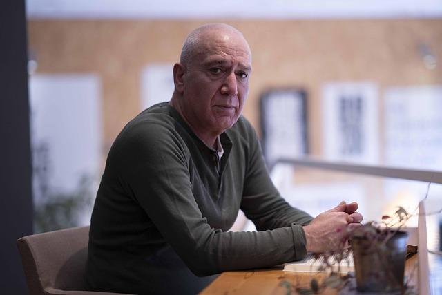 A right-side view of Alexis Karpouzos sitting at a desk looking at us.