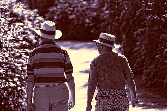 A sepia image of two old men wearing hats walking away from us.