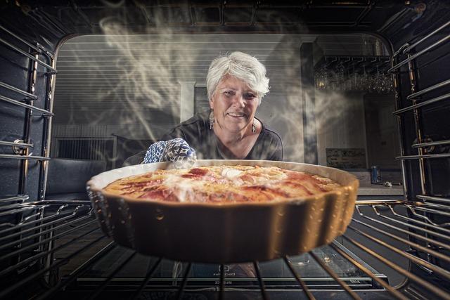 A white-haired woman reaching into the oven to pull out a pie, from the perspective inside the oven.