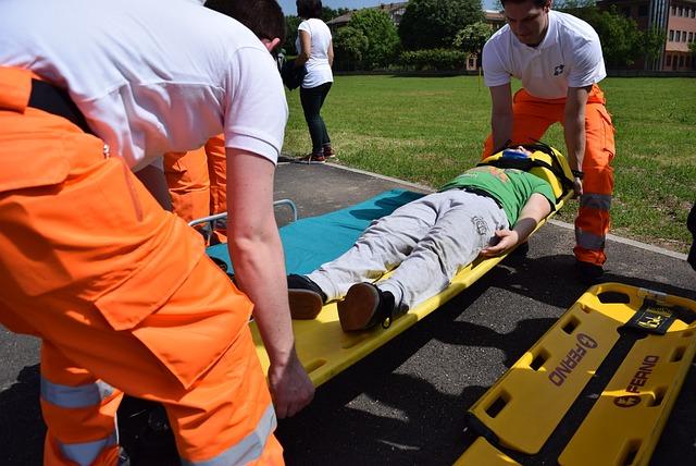 Two paramedics lifting a stretcher with a child strapped onto it.