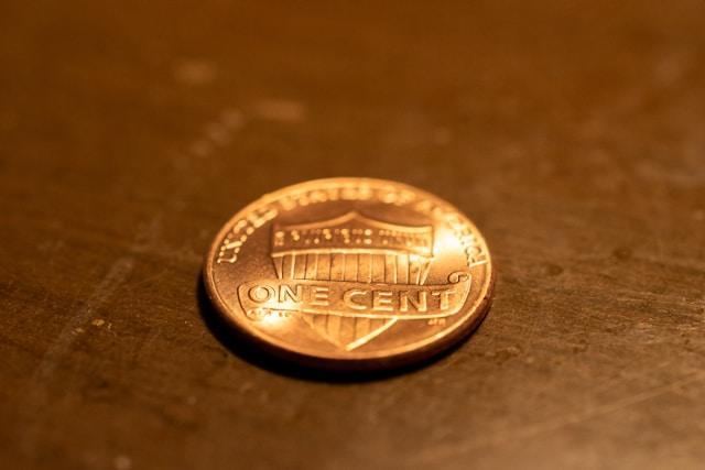 A penny sitting on a brown surface, tails side up.