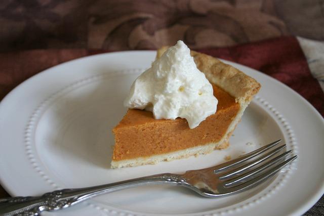 A piece of pumpkin pie with ice-cream on a white plate.