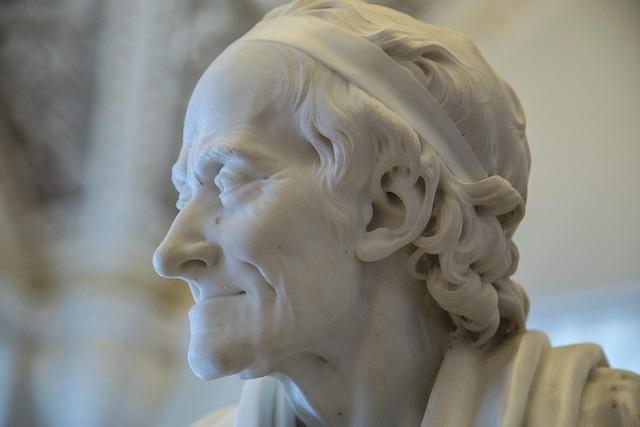 A close-up of a white marble statue of Voltaire.