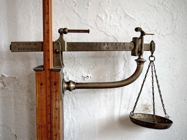 An old-style scale with a single pan and a wooden bar.