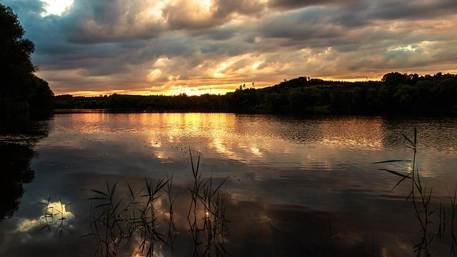 Early morning overlooking a lake with hills in silhouette against a cloudy morning sky.