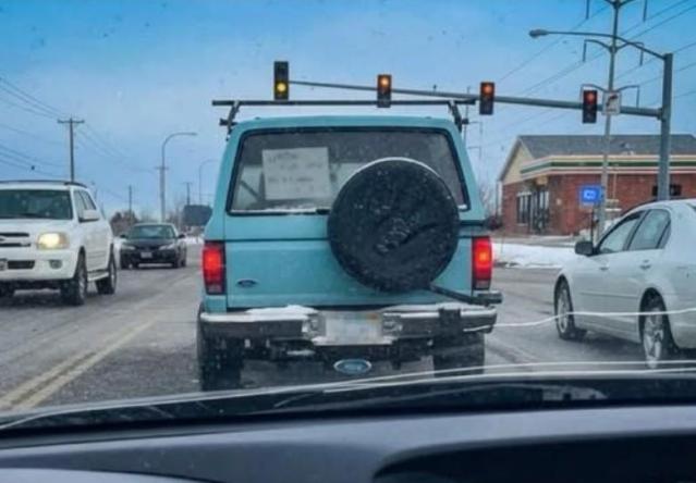 A hand-written sign in the back window of an SUV stopped at a traffic light in winter.