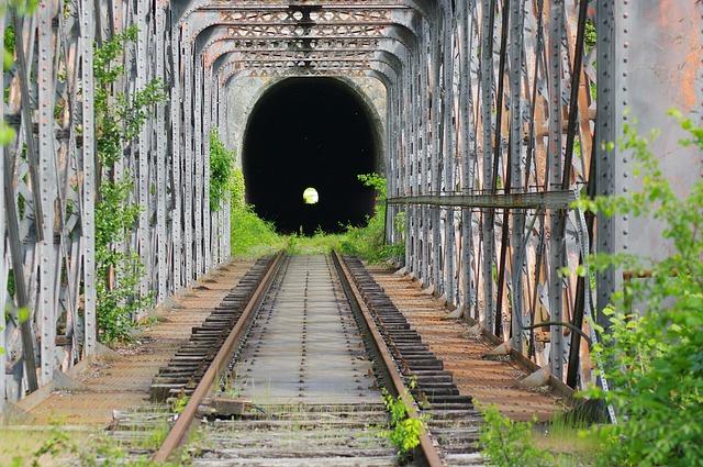 A train tunnel in the daytime with the tiniest glimmer of light at the far end.