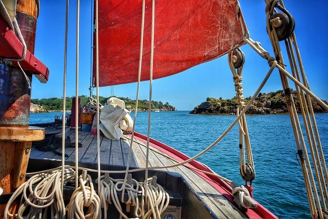 A view from on deck of a sailing ship sailing between islands.