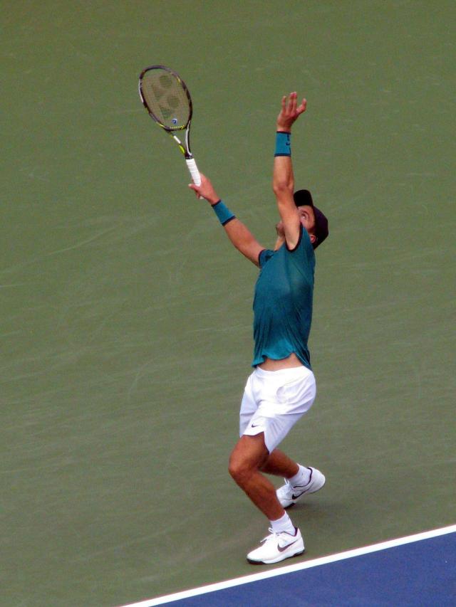 A tennis player throwing the ball in the air ready for a whopping serve.