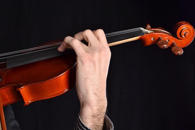 Only the neck of a violin and the violinist's left hand are visible against a black background.