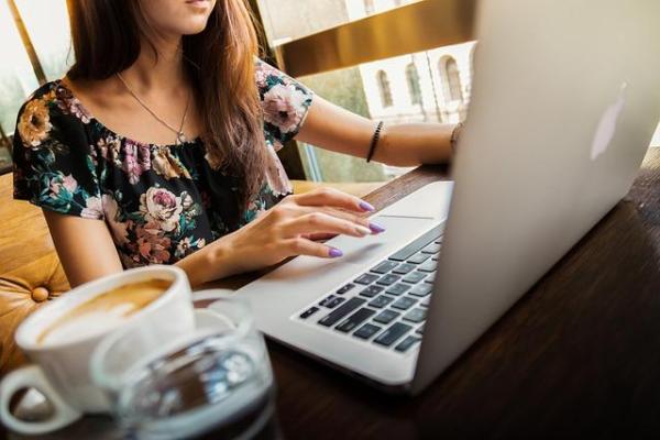 young woman sitting at a desk with a laptop and coffee in the foreground.