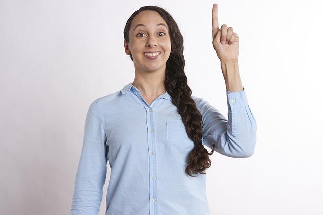 A woman in a blue shirt, one finger in the air having come up with a great idea.