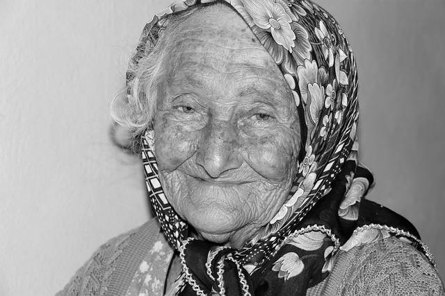 A black and white image of an old woman wearing a head scarf.
