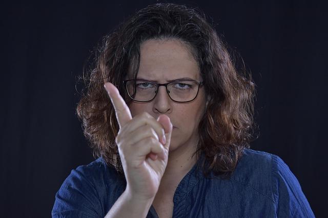 A woman glaring directly at us while holding a pointer finger up in warning.