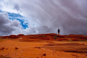 A lone person standing at the crest of a desert ridge as pre-hurricane clouds fill the air.