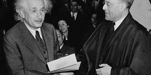 A photo of Einstein shaking hands with another scholar who is looking at him with admiration.