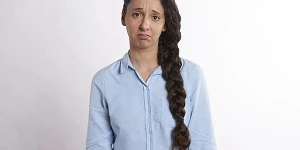 A woman with a long braid and a blue shirt, looking very sad.