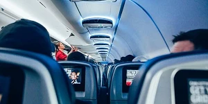 The inside of a passenger plane, looking toward the front of the plane between the seats.
