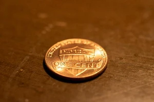 A penny sitting on a brown surface, tails side up.