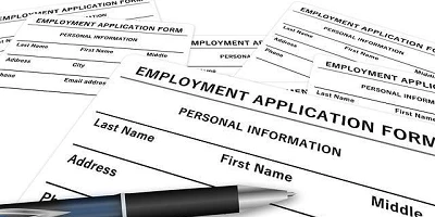 Blank job application papers on a desk with a pen sitting on top.