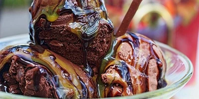 A close-up of ice-cream covered in butterscotch and chocolate syrup.