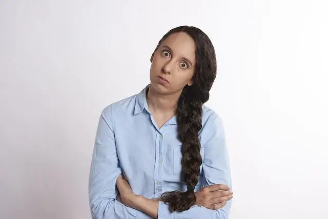 A woman in a blue shirt with a long braid looking angry.