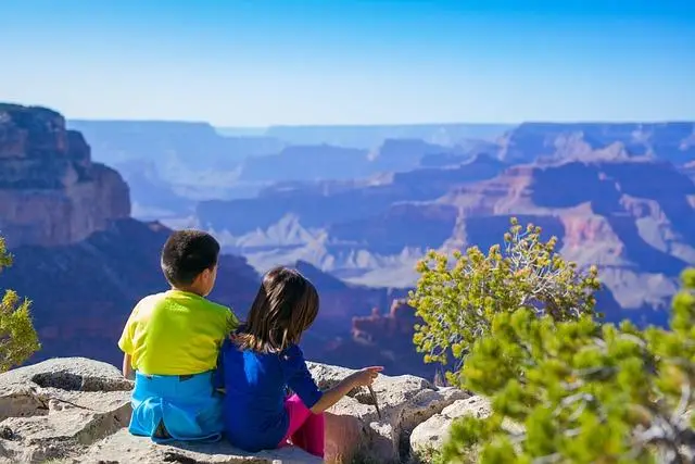 Two young children sitting on a rock looking out over the Grand Canyon.